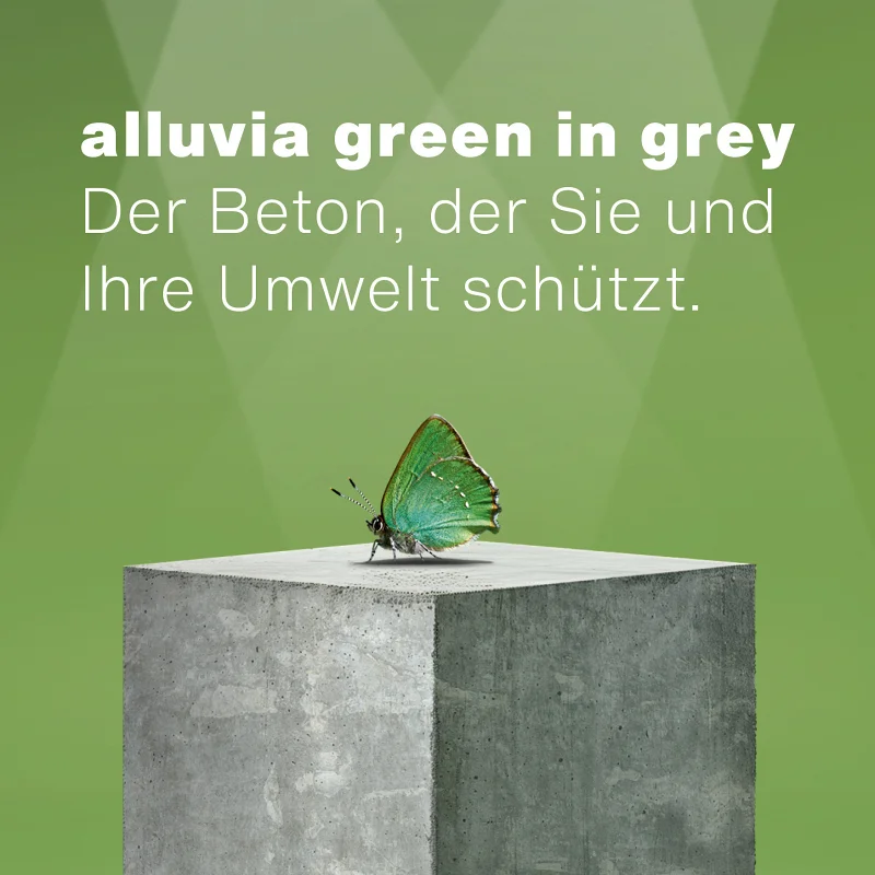 Betonkubus vor grünem Hintergrund im Schweinwerfer Licht, mit einem grünen Schmetterling darauf.