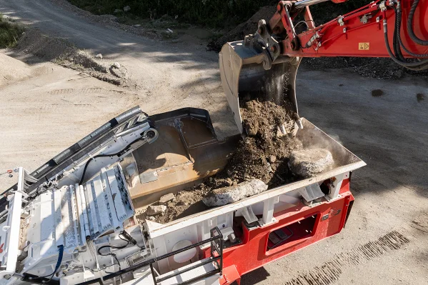 Ein Bagger befüllt einen Brecher mit Mischabbruchmaterial