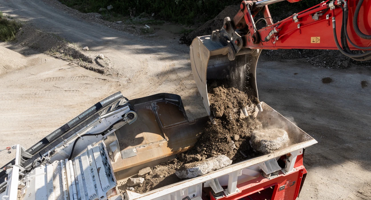 Ein Bagger befüllt einen Brecher mit Mischabbruchmaterial
